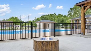 Zona de piscina amb una xemeneia de fusta i un pati tancat per una tanca.