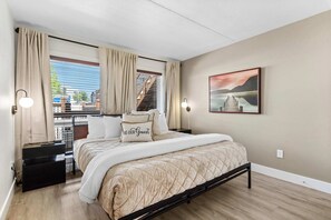 Une chambre à coucher avec un lit, des rideaux, un tableau et une table de chevet.