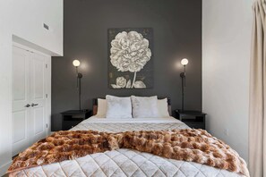 Ein Schlafzimmer mit einem großen Bett, zwei Nachttischen, einem Wandbild und einer Tür.