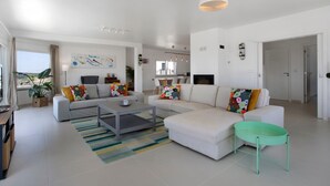 A modern living room with a sofa, coffee table, and a small table with a tray. - Room 'Earth' with Mountain View, Shared Pool and Wi-Fi (Lourinhã)