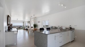 A modern kitchen with a granite countertop, white cabinetry, and a view of the landscape. - 'Venus' Room with Mountain View, Shared Pool and Wi-Fi Access (Lourinhã)