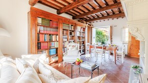A spacious living room with a high wooden ceiling, a large bookshelf, a dining area with a table and chairs, and a cozy seating area with a sofa. - Smart Panoramic Farmhouse Jacuzzi in Montecatini Alto (Montecatini alto)