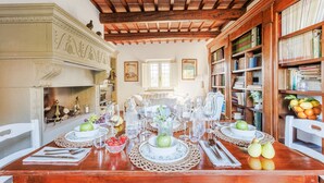 A dining area with a wooden table set for four, surrounded by bookshelves filled with books. - Smart Panoramic Farmhouse Jacuzzi in Montecatini Alto (Montecatini alto)