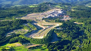 Vista aérea de una pista de carreras rodeada de exuberantes colinas y bosques verdes.