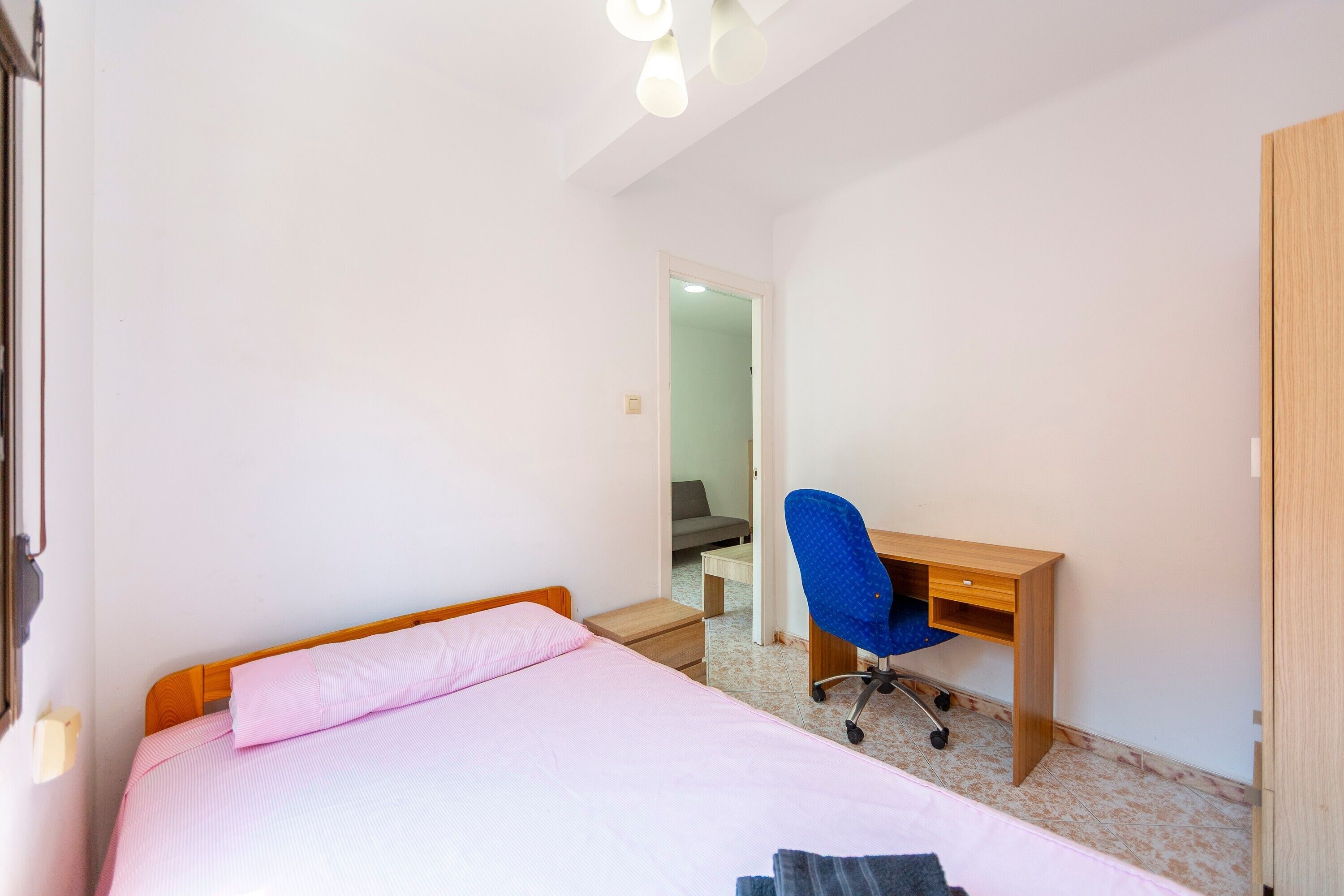 A bedroom with a bed, a desk, and a chair.