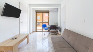 A living room with a TV, a sofa, a table, and a chair. - Bright Apartment 'Zapillomotril' with Air Conditioning (Almería)