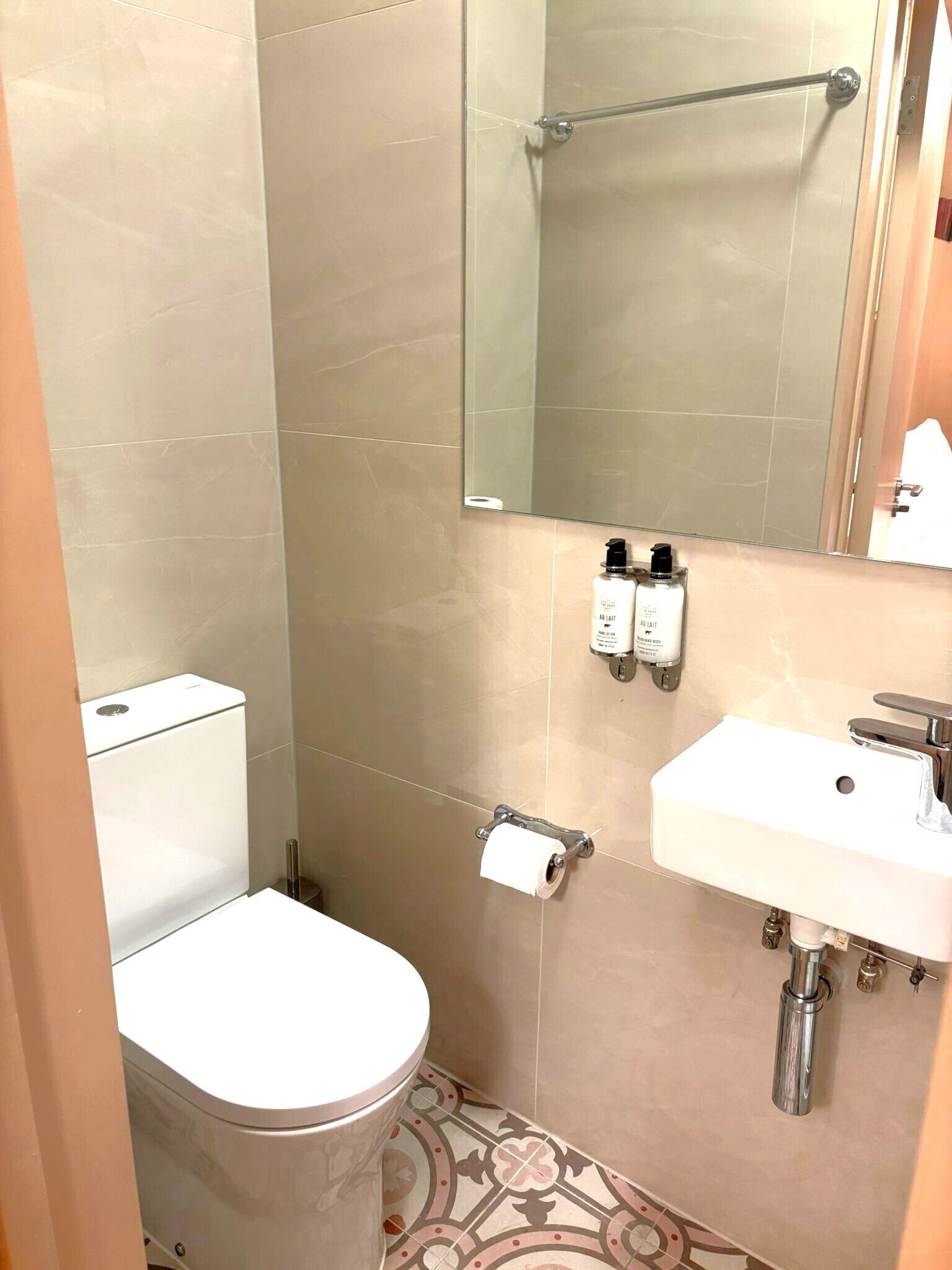 A small bathroom with a toilet, a sink, a mirror, and a shower area.