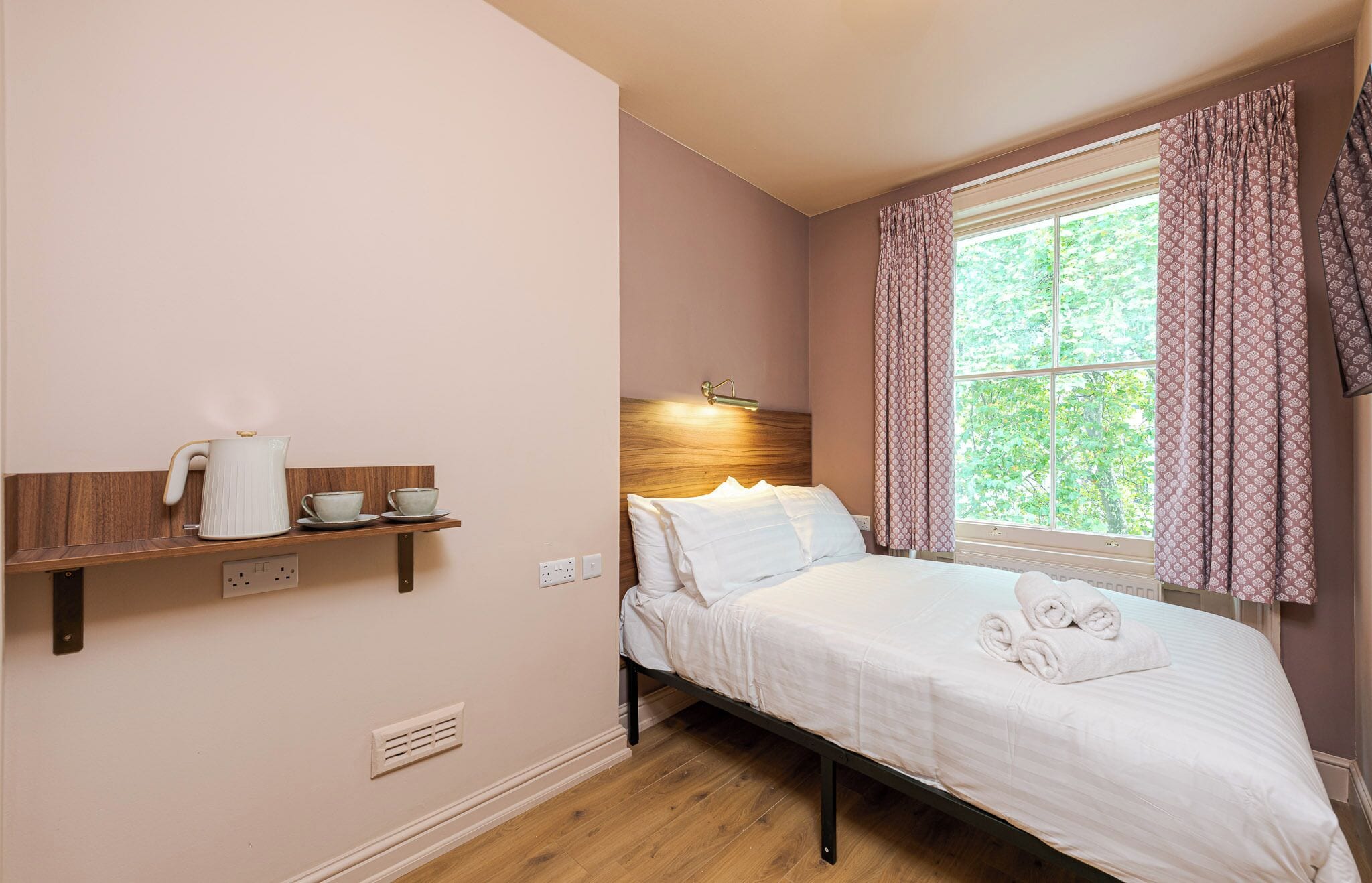 A bedroom with a bed, bedside table, and a window with curtains.