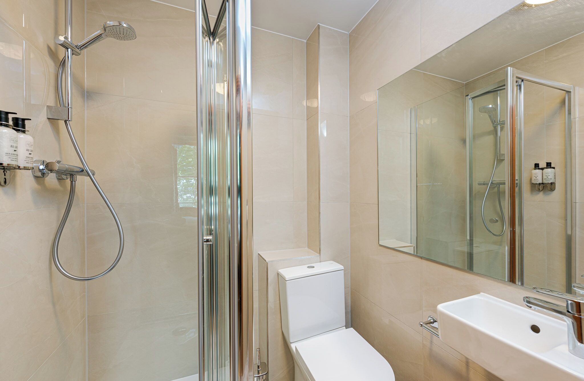 Un baño moderno con ducha envuelta en vidrio, inodoro y lavamanos.