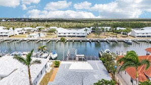 A marina with several boats docked, surrounded by white buildings with red-tiled roofs, and palm trees. - Tranquility Waters (Fort Myers Beach)