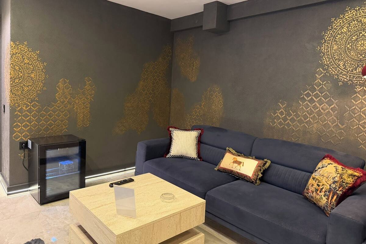 Ein modernes Wohnzimmer mit einem dunkelblauen Sofa, gemusterten Kissen, einem Holztisch und einer schwarzen Unterhaltungseinheit.