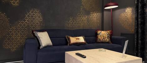 A dark blue sofa with patterned cushions, a wooden coffee table, and a red floor lamp in a modern living room.