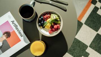 Una mesa con un bol de fruta, una taza de café y un vaso de zumo de naranja.