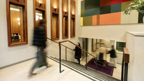 A modern interior with wooden paneling, a staircase, and a colorful wall art piece.