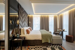 A modern hotel room with a large bed, a desk, a chair, and a small table with a drink. - The Wellington Glasgow By Adina (Glasgow)