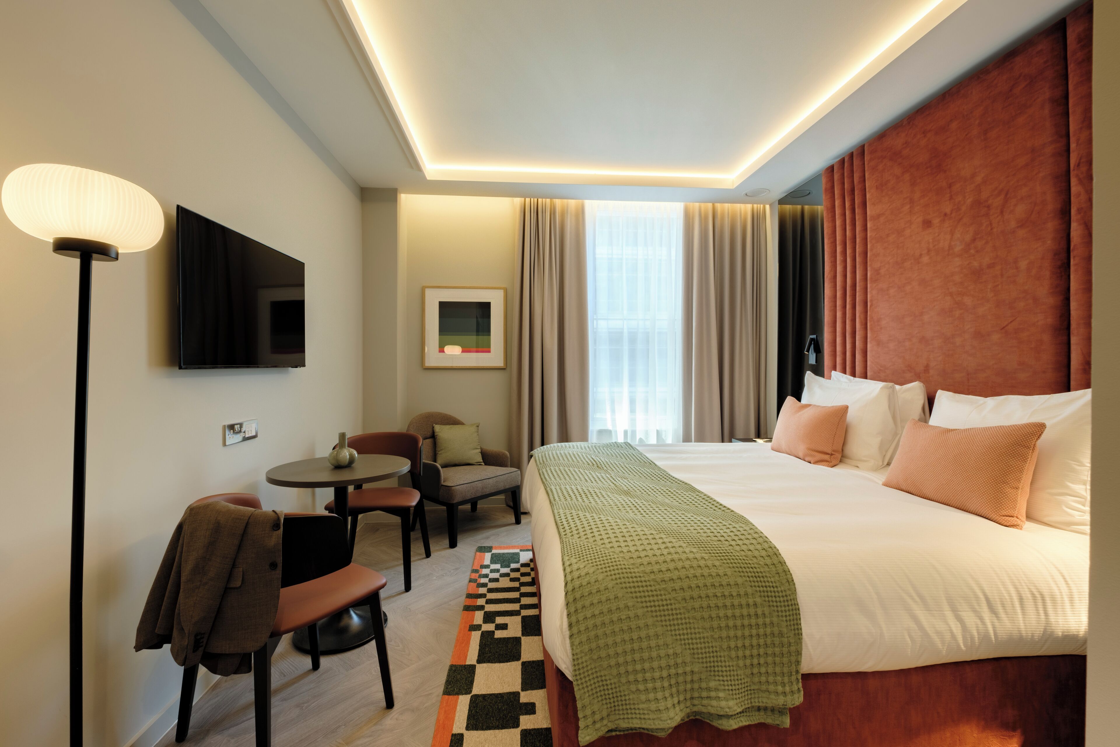 Una habitación de hotel con una cama, televisión, escritorio y una silla.