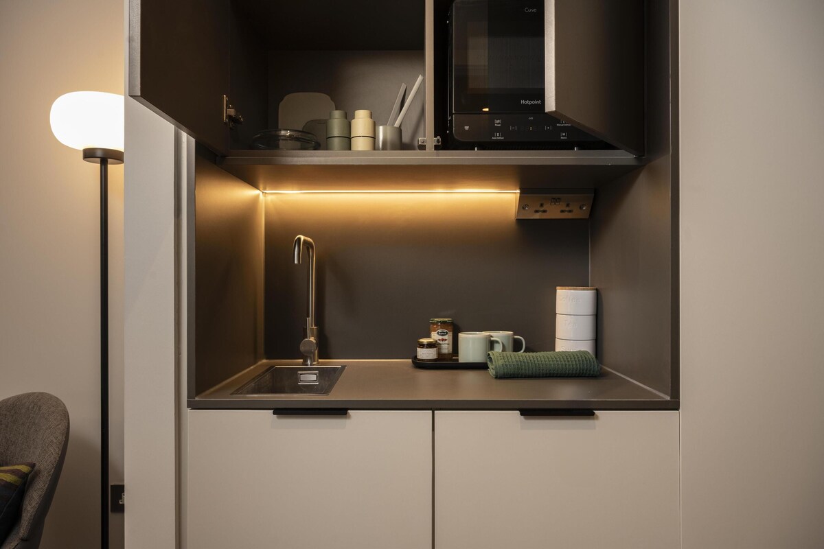 A compact kitchenette with a built-in microwave, a sink, and a small countertop area.