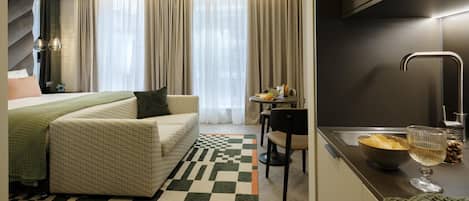 Een moderne hotelkamer met een bed, een zithoek, een eethoek en een keuken.