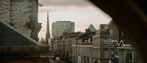 A city street with historic buildings, a modern glass skyscraper, and a view through a car window.