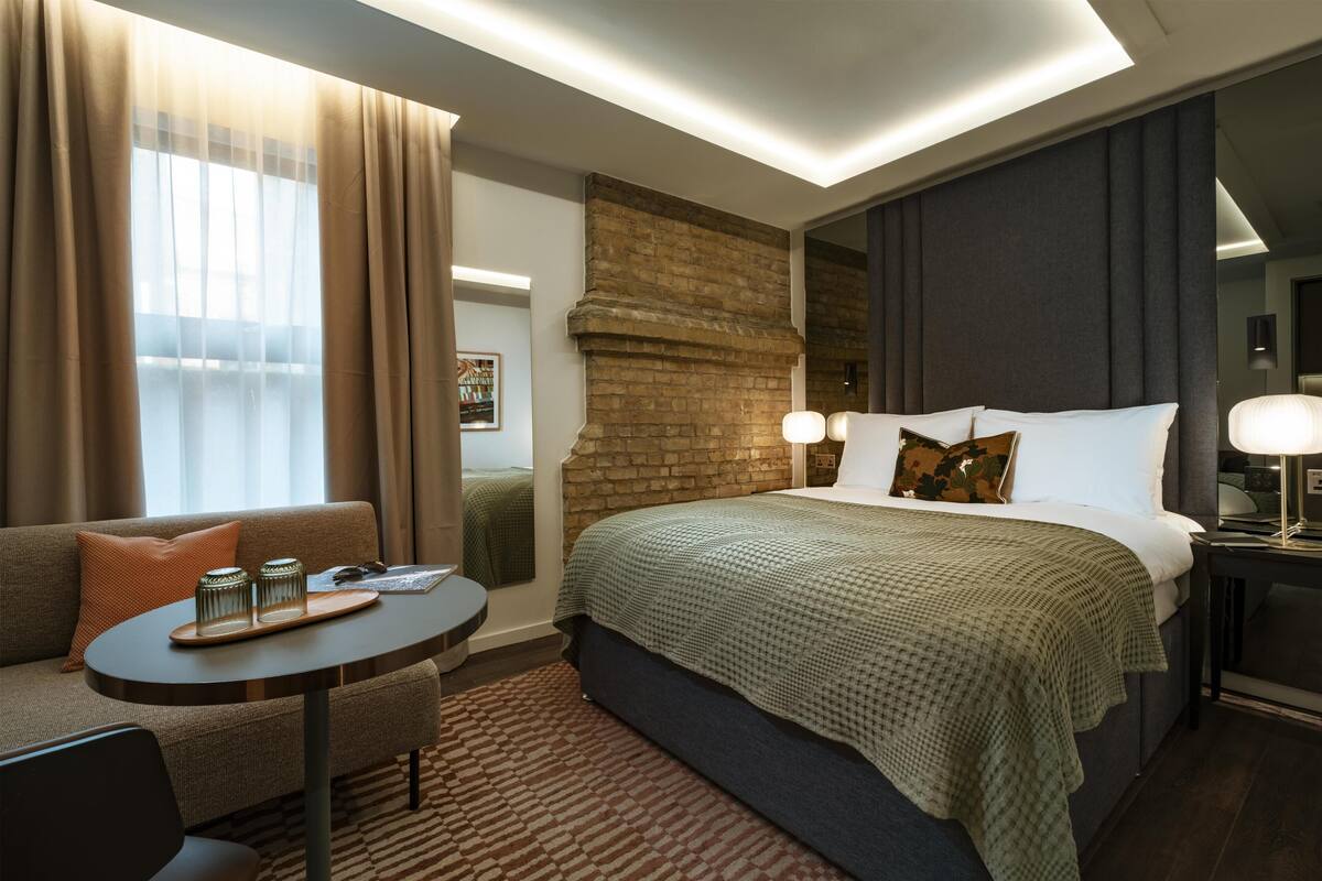 Una habitación de hotel con una cama, un sofá, una mesita y una mesita de noche.