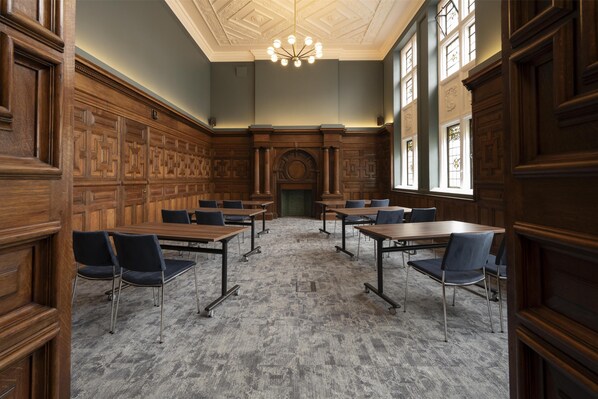 A conference room with wooden paneling, a chandelier, and a fireplace. - The Hobson Cambridge By Adina (Cambridge)