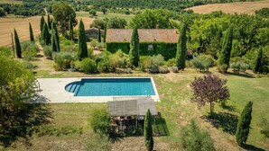 A villa with a swimming pool, surrounded by lush greenery and hills.
