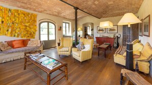 A spacious living room with a brick ceiling, a sofa, armchairs, a coffee table, and a fireplace.