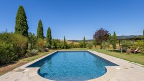 A rectangular swimming pool with a curved edge, surrounded by a stone deck.