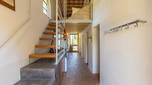 A staircase with a wooden finish, a metal railing, and a tiled floor.