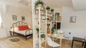 Una camera da letto moderna e luminosa, con un letto, un comodino e una libreria piena di libri e oggetti decorativi.