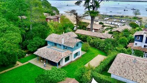 Una propietat costanera amb una casa gran, un jardí ben cuidat i vista al mar amb vaixells.
