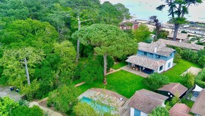 Una casa espaiosa amb piscina, envoltada de vegetació exuberant i una platja al fons.