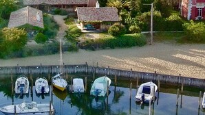 Un port esportiu amb diverses embarcacions amarrades, envoltat de cases i vegetació.