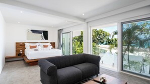 A modern bedroom with a large bed, a dark sofa, and a wooden coffee table.