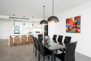 Una cocina moderna con armarios blancos, una isla central e iluminación colgante.