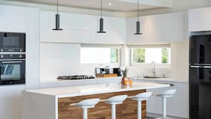 A modern kitchen with white cabinetry, a central island with bar stools, and a built-in oven.