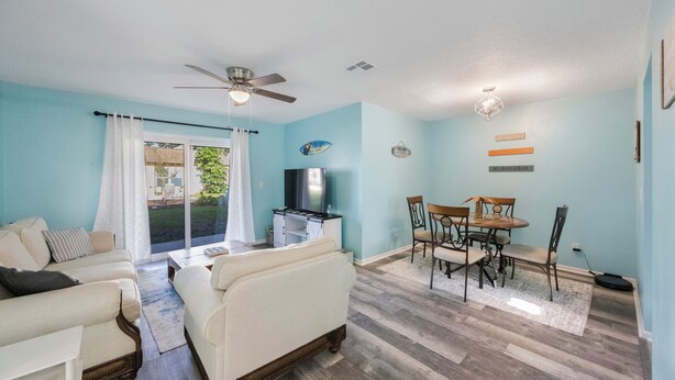 A living room with a sofa, a TV, and a dining area with chairs and a table.