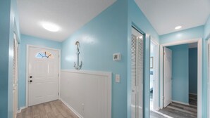 A hallway with light blue walls, white doors, and a wooden floor.