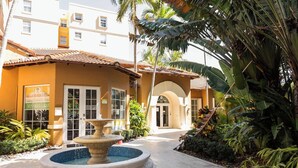 Un hôtel doté d’une fontaine, de palmiers et d’une cour dallée.