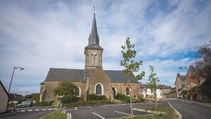 A church with a tall steeple and a parking lot in front.