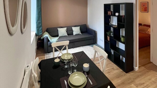 A compact living space with a dining area, a sofa, and a bookshelf.