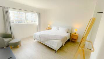 Een slaapkamer met een bed, bureau, stoel, lamp en een lessenaar.