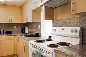 A kitchen with a white stove, granite countertop, and wooden cabinets.