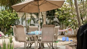 Une terrasse extérieure avec une table et des chaises, entourée de verdure et ornée d’une fresque murale.