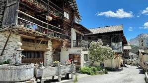 Ein traditionelles Holzhaus mit Balkonen, einer Steinmauer und blauem Himmel.