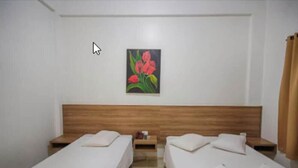 A room with two single beds, wooden headboards, a small table with a lamp, and a painting of red flowers on the wall. - Samambaia Hotel (Foz do Iguaçu)