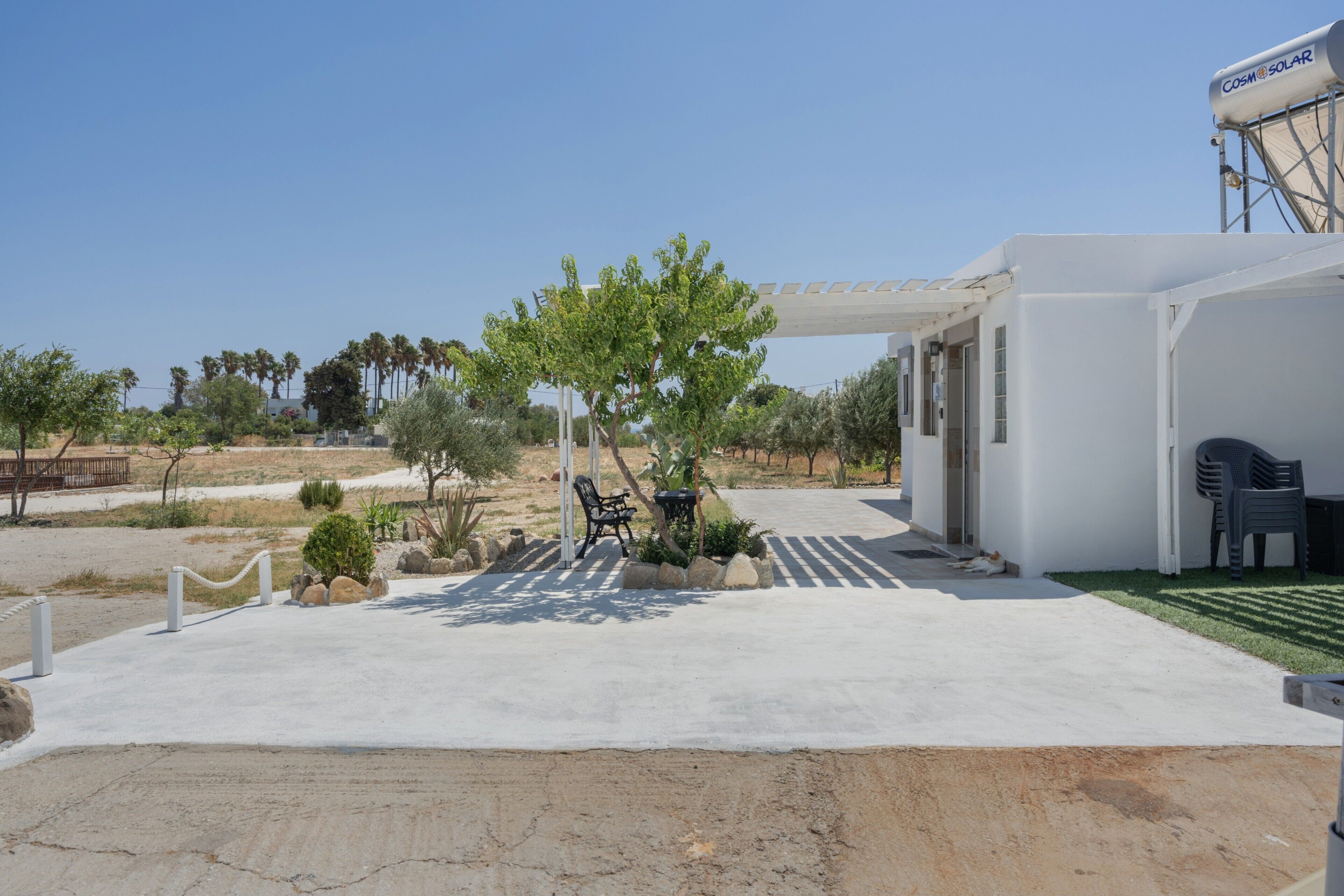 Ein modernes Gebäude mit überdachter Terrasse, Außenbestuhlung und Solar-Warmwasseranlage.