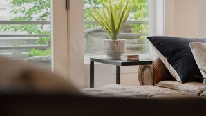 Ett mysigt vardagsrum med en soffa, ett litet bord med en växt och utsikt över grönskan utanför.