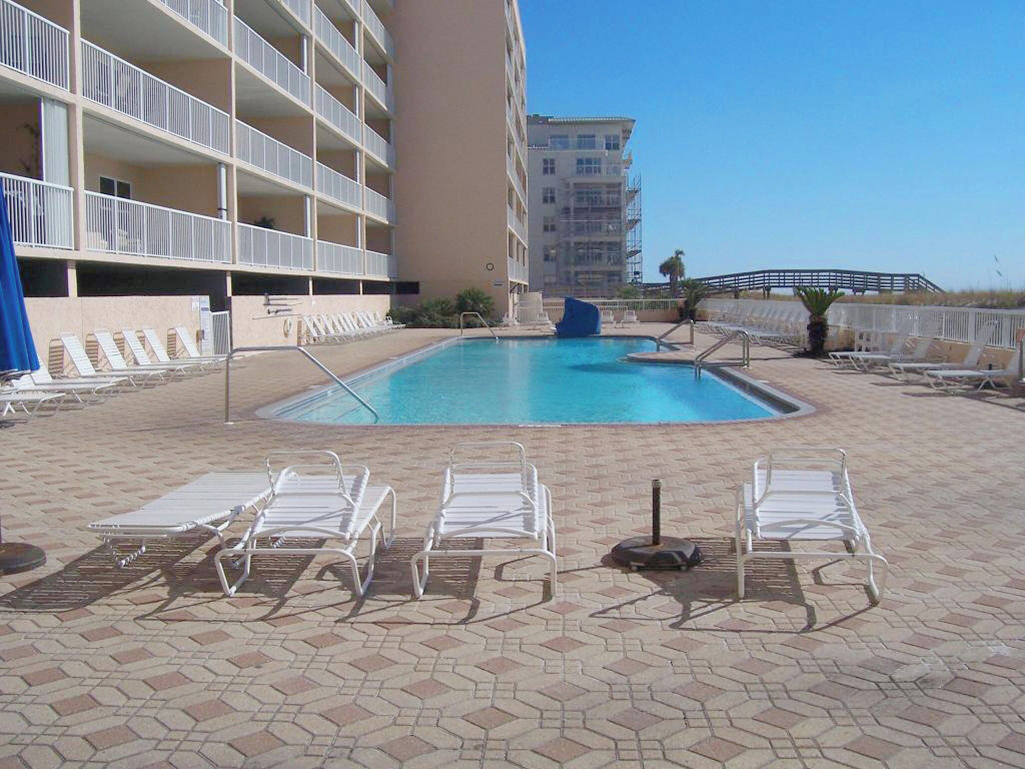 Una piscina con lettini, uno scivolo e un edificio con numerosi balconi.