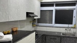 Una cocina moderna con encimeras de mármol, horno empotrado y ventana con persianas.